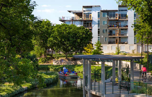 A modern building is situated next to a river with a bridge crossing over it.