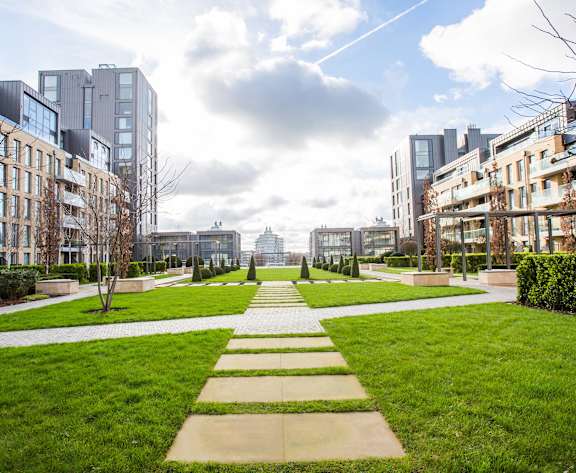 a park with grass and buildings in the background
