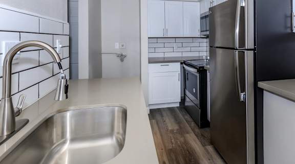 A modern kitchen with a stainless steel refrigerator and a sink with a faucet.