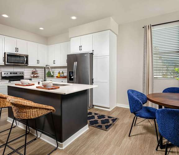 A kitchen with a black island and white cabinets.