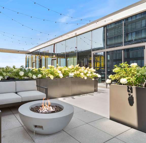 A modern outdoor seating area with a fire pit and planters.