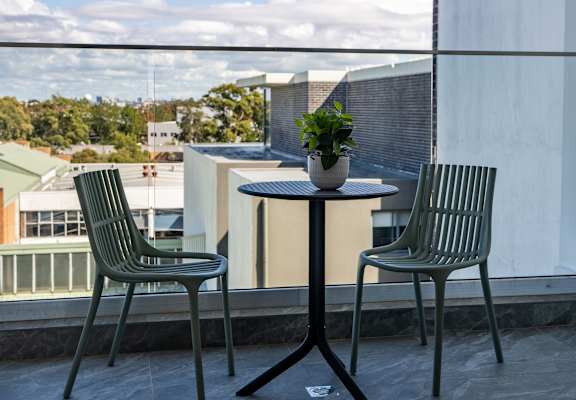 a table with two chairs and a potted plant on a balcony