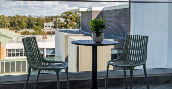 a table with two chairs and a potted plant on a balcony