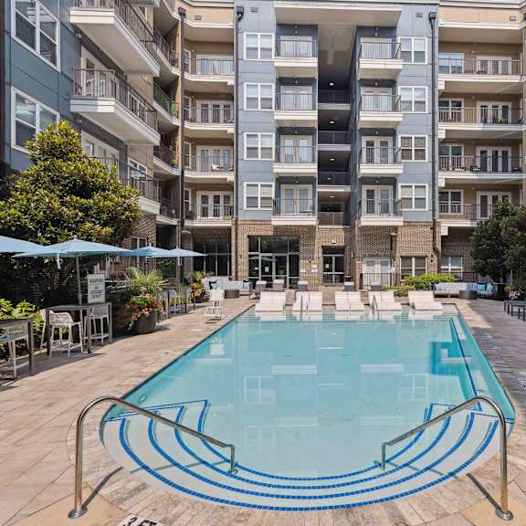 A swimming pool in front of a multi-story residential building.