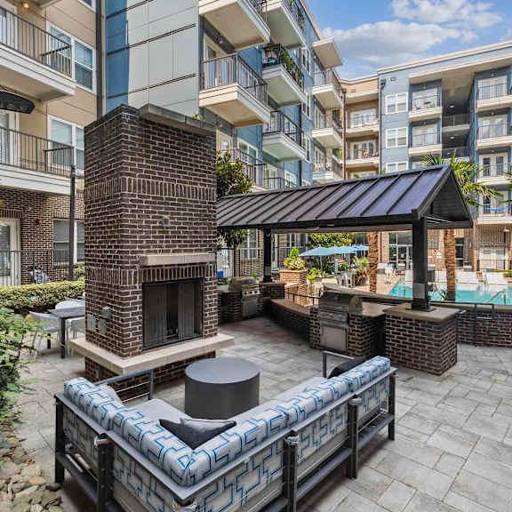 A patio with a brick fireplace and a black and white couch.