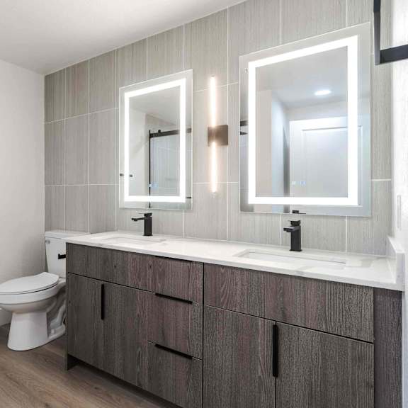 A bathroom with a toilet, sink, and mirrors.
