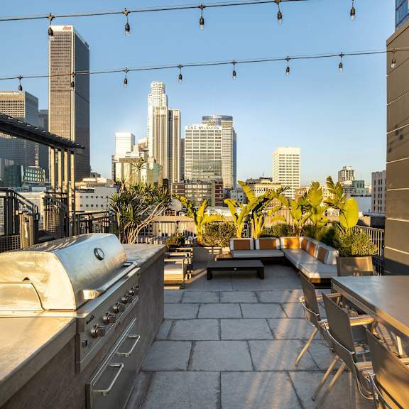 A rooftop patio with a grill and a view of the city skyline.