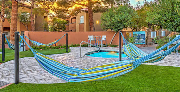 A hammock is strung between two trees in a backyard.