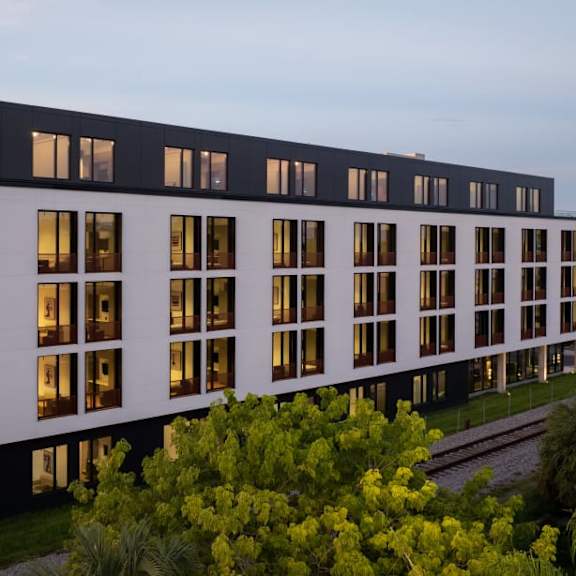 A modern building with a lot of windows and trees in front.
