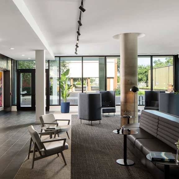 A modern waiting room with a long sofa, chairs, and a table with a vase of flowers on it.