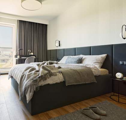 A bedroom with a large bed and a window overlooking a cityscape.