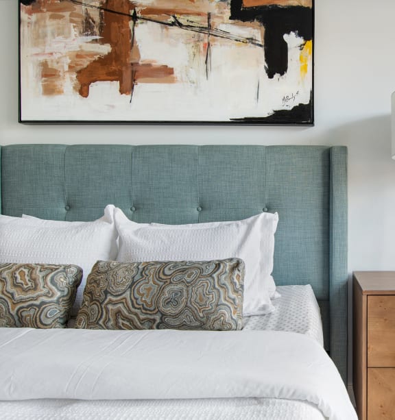 a bedroom with a bed and a painting on the wall