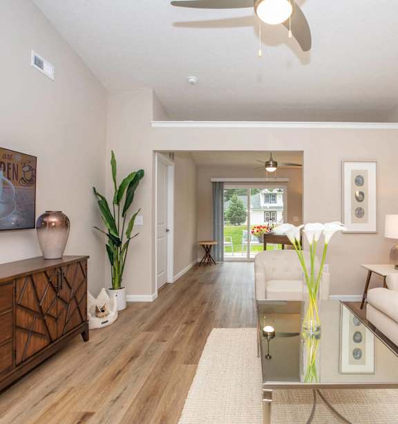 A living room with a wooden floor and a ceiling fan.