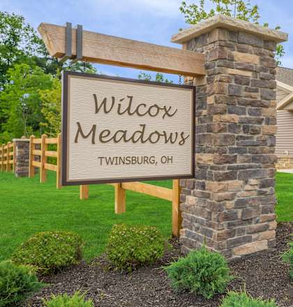 A sign that says "Wilcox Meadows" in front of a stone pillar.