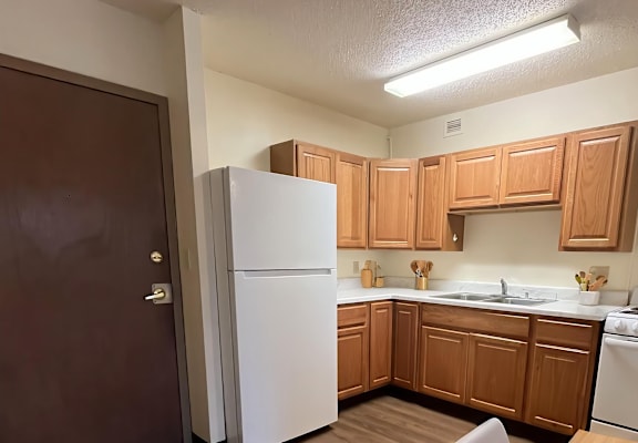 A kitchen with wooden cabinets and a white refrigerator.