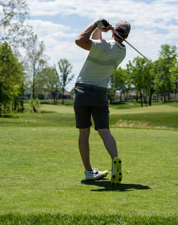 A man is playing golf on a sunny day.