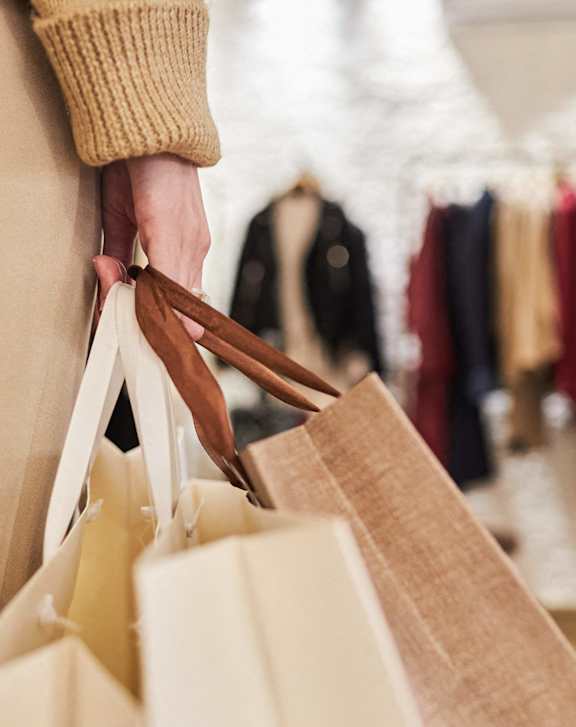 A person holding a brown paper bag in a store.