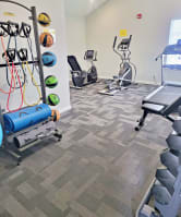 a gym with cardio equipment and weights at the district at highland village apartments