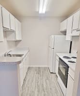 an empty kitchen with white appliances and white cabinets