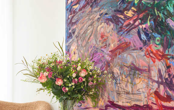 Living room detail showing a colourful abstract painting above a walnut sideboard.