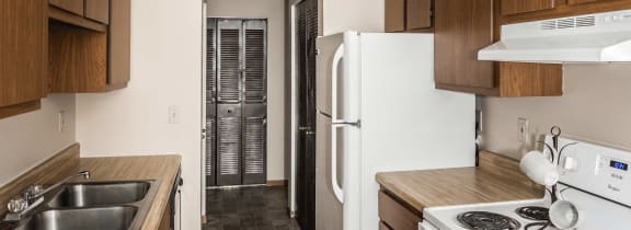 Grand Forks, ND Barrette Arms Apartments. a kitchen with white appliances and wooden cabinets