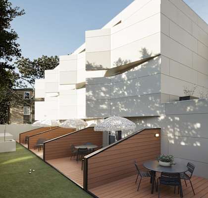 a terrace with a table and chairs in front of a white building