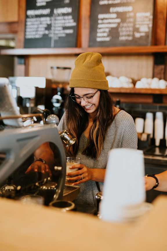 a woman in a barber shop with a glass of coffee