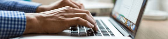 A person is typing on a laptop keyboard.