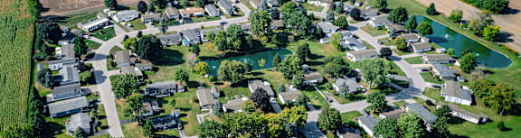A bird's eye view of a neighborhood with a pond in the center.