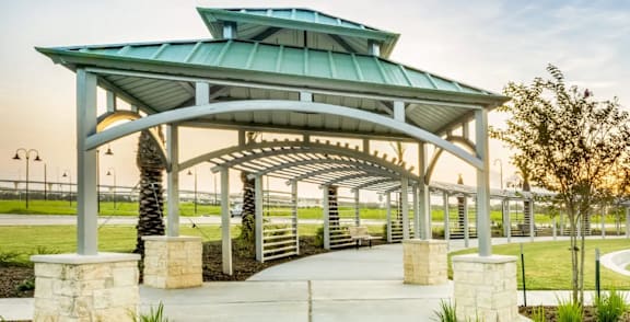 A pavilion with a green roof is surrounded by a winding walkway and palm trees.