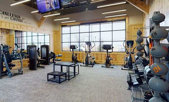 A gym with a variety of equipment including weights and a television.