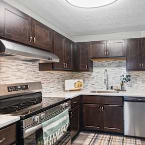 A kitchen with a stove top oven, a refrigerator, and a counter top.