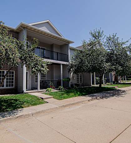 an apartment building with a sidewalk and trees in front of it at Diamond Brooke, West Des Moines, 50266