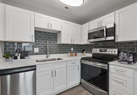 A kitchen with white cabinets and a black stove top oven.