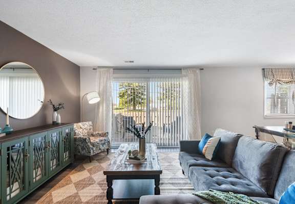 A living room with a grey couch, a wooden coffee table, and a green cabinet.
