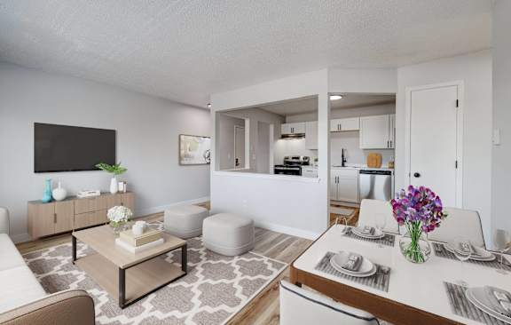 A modern living room with a white sofa, a coffee table, and a dining table set for two at The Hampton Meadows Apartments, Iowa, 50315
