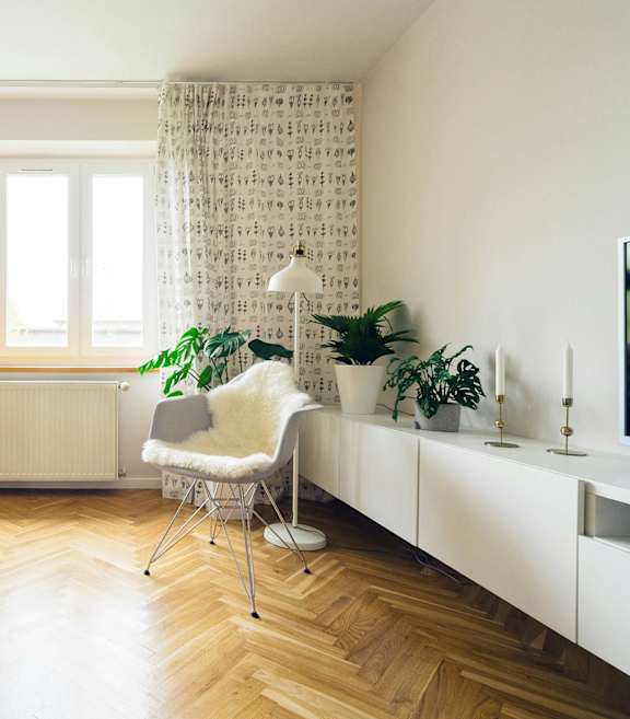 A blue sofa sits in a living room with a white chair and a television.