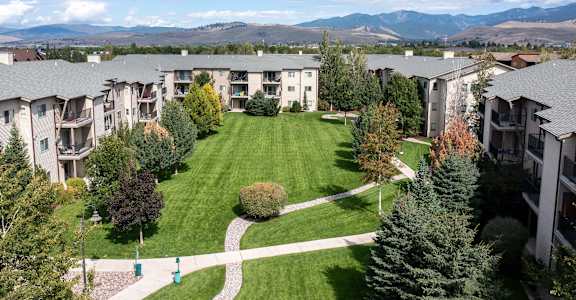 an aerial view of an apartment complex with a lawn and trees