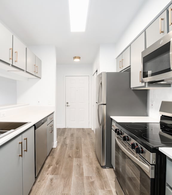 A modern kitchen with stainless steel appliances and wooden flooring.