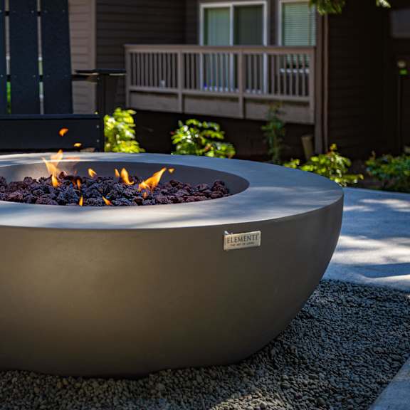 A modern fire pit with flames burning in it.