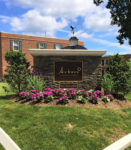 a brick building with a sign in the middle of a grassy area