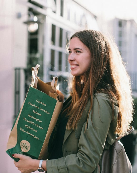 a woman holding a paper bag of food