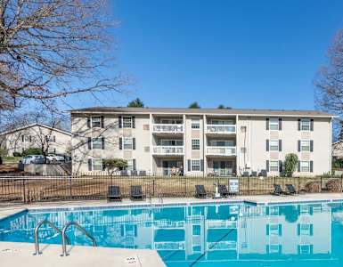 A swimming pool in front of a white apartment building.