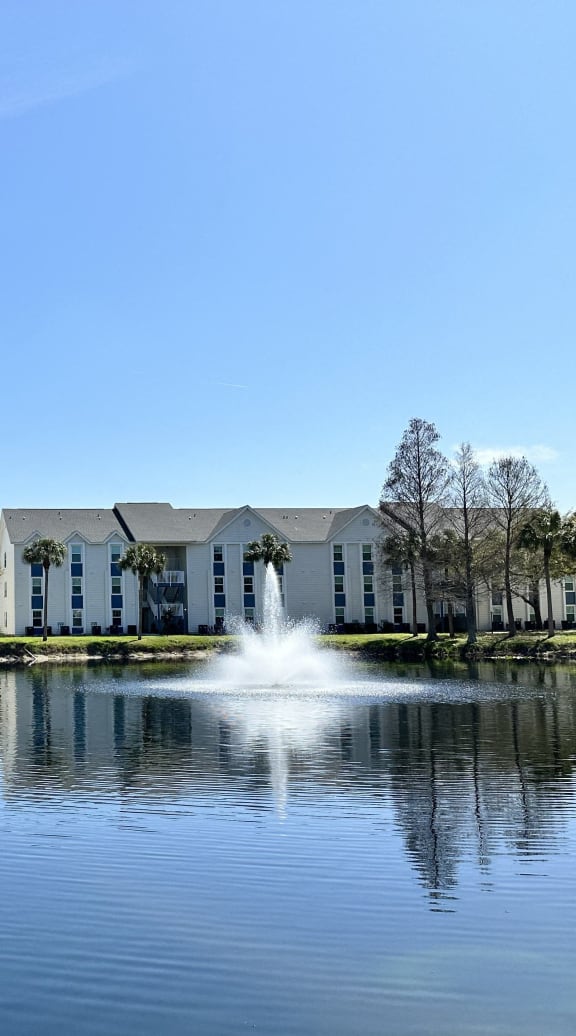 a fountain in the middle of a pond in front of a building