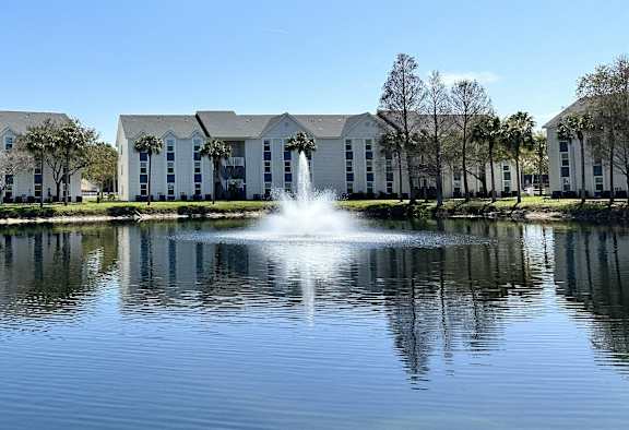 a fountain in the middle of a pond in front of a building