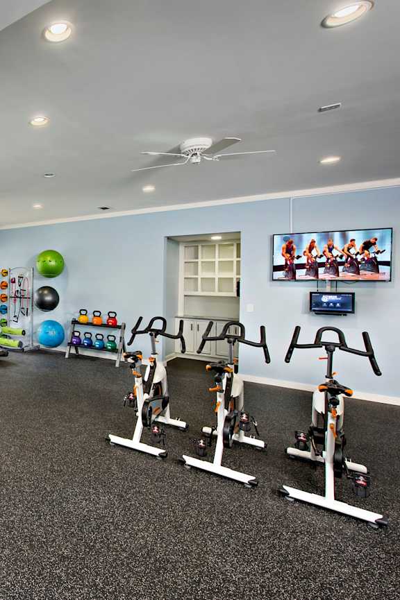 A gym with exercise equipment and a TV on the wall.
