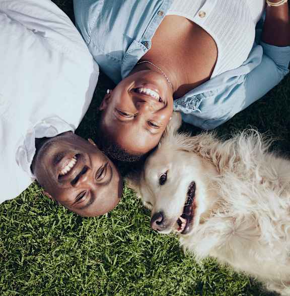 A man and woman lying on the grass with a dog.