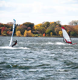 a person windsurfing on a lake with trees in the background