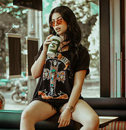 A women sitting on top of a booth sipping a soda.