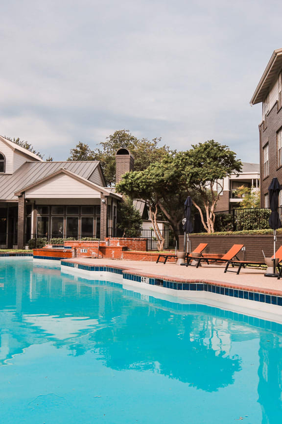 a swimming pool with orange chairs and a building in the background